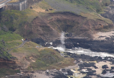 [A plume of water approximately 20-30 foot high is seen above the ground at the shoreline.]